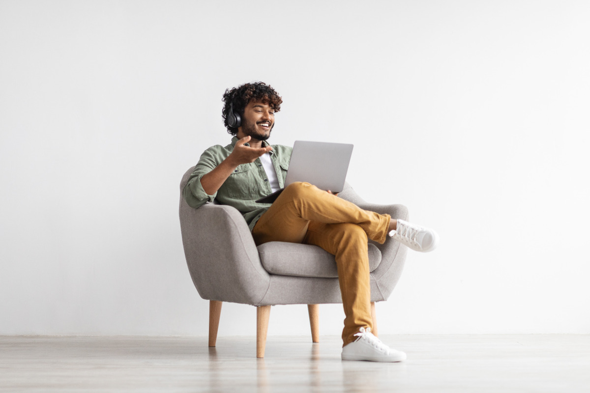 Smiling man sitting in chair holding a laptop